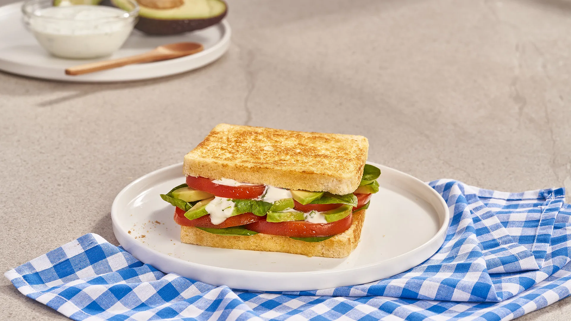 Sándwich de aguacate, tomate, hojas de espinaca y salsa de yogur casera