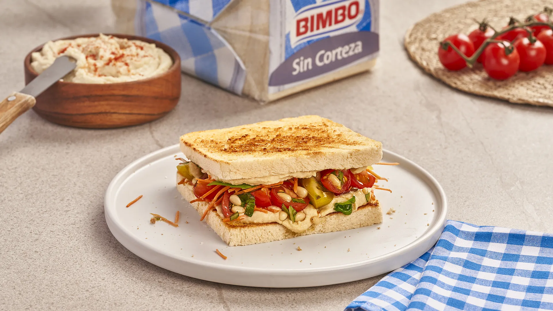 Sándwich de hummus, zanahoria rallada, tomate cherry y un aliño de albahaca fresca y piñones